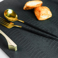 Close-up of a black octagon serving tray with a spoon and two biscuits visible. The background is blurred, focusing on the tray and its contents.